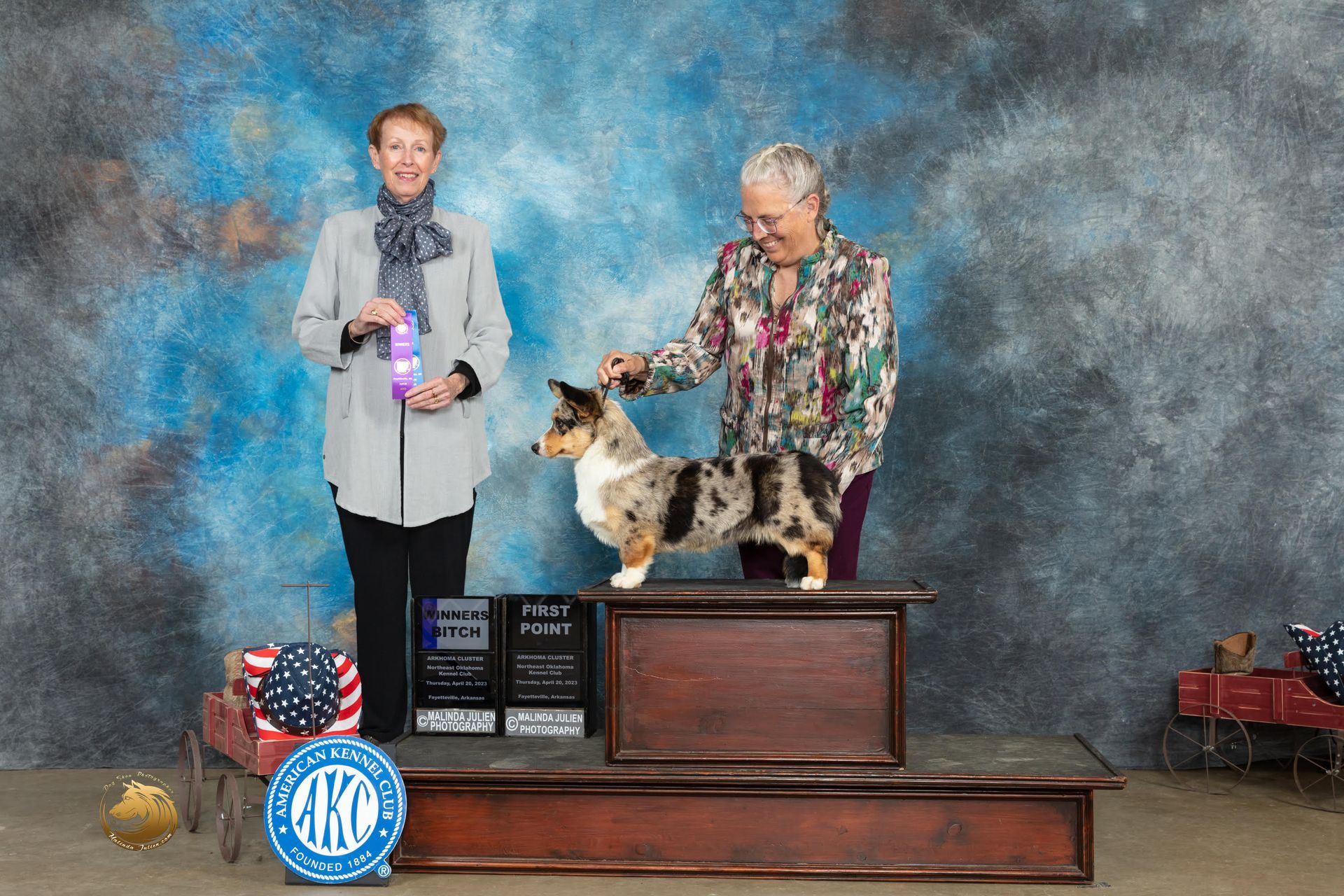 Two women are standing next to a dog on a podium at a dog show.