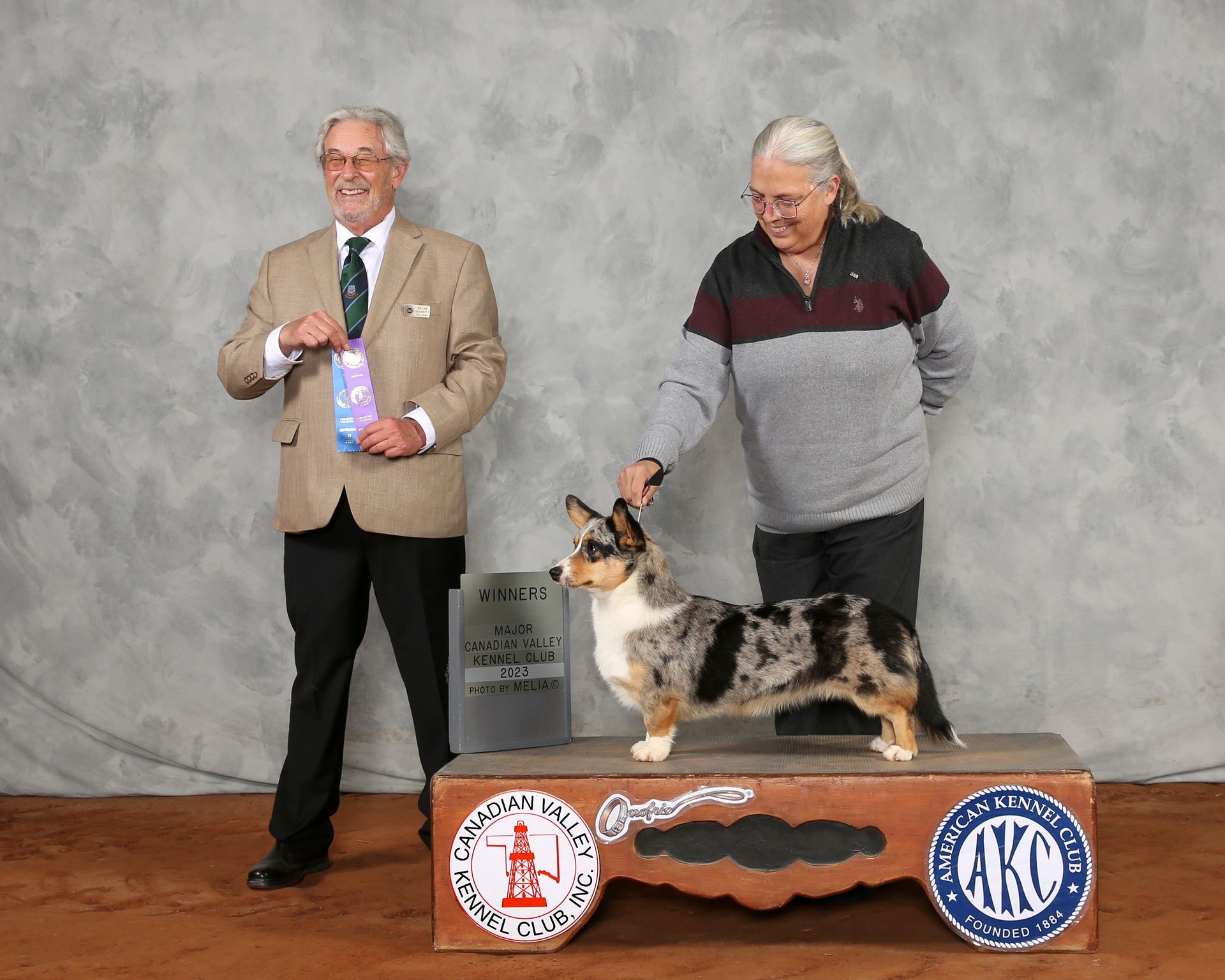 A man and a woman standing next to a dog on a podium