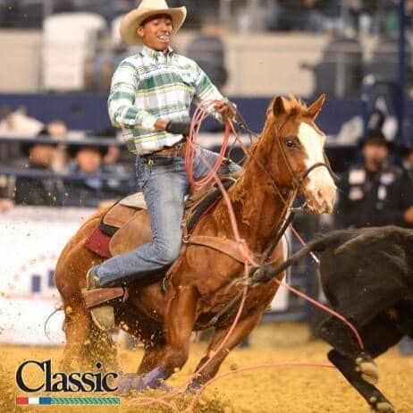 A man in a cowboy hat is riding a horse in a rodeo