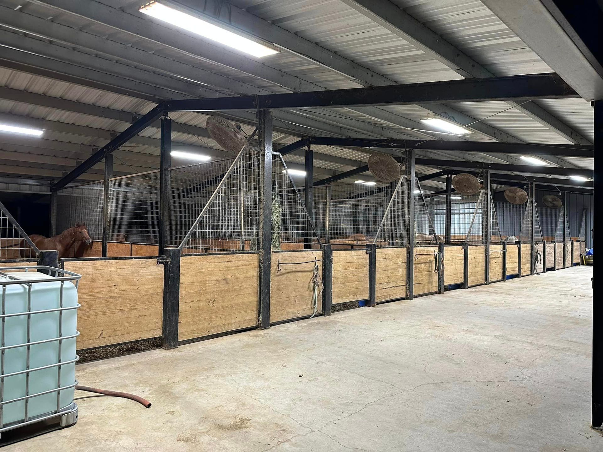 A large stable with a lot of horses in it.