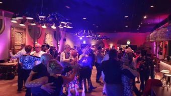 Mensen dansen in een danszaal/club met kleurrijke verlichting.