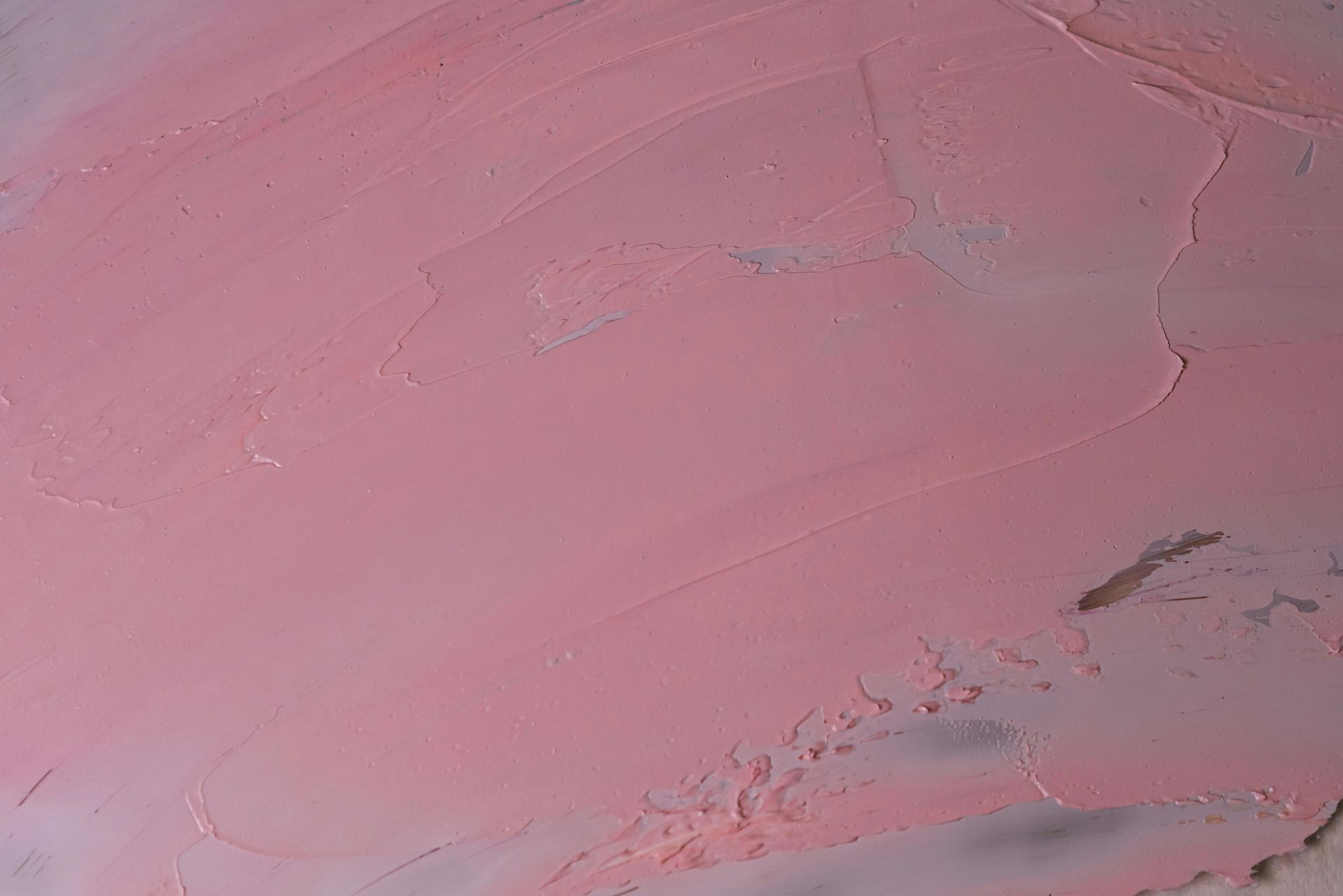 Een close-up van een dikke,  roze verfvlek op een oppervlak, met zichtbare penseelstreken en subtiele donkere onderlagen.