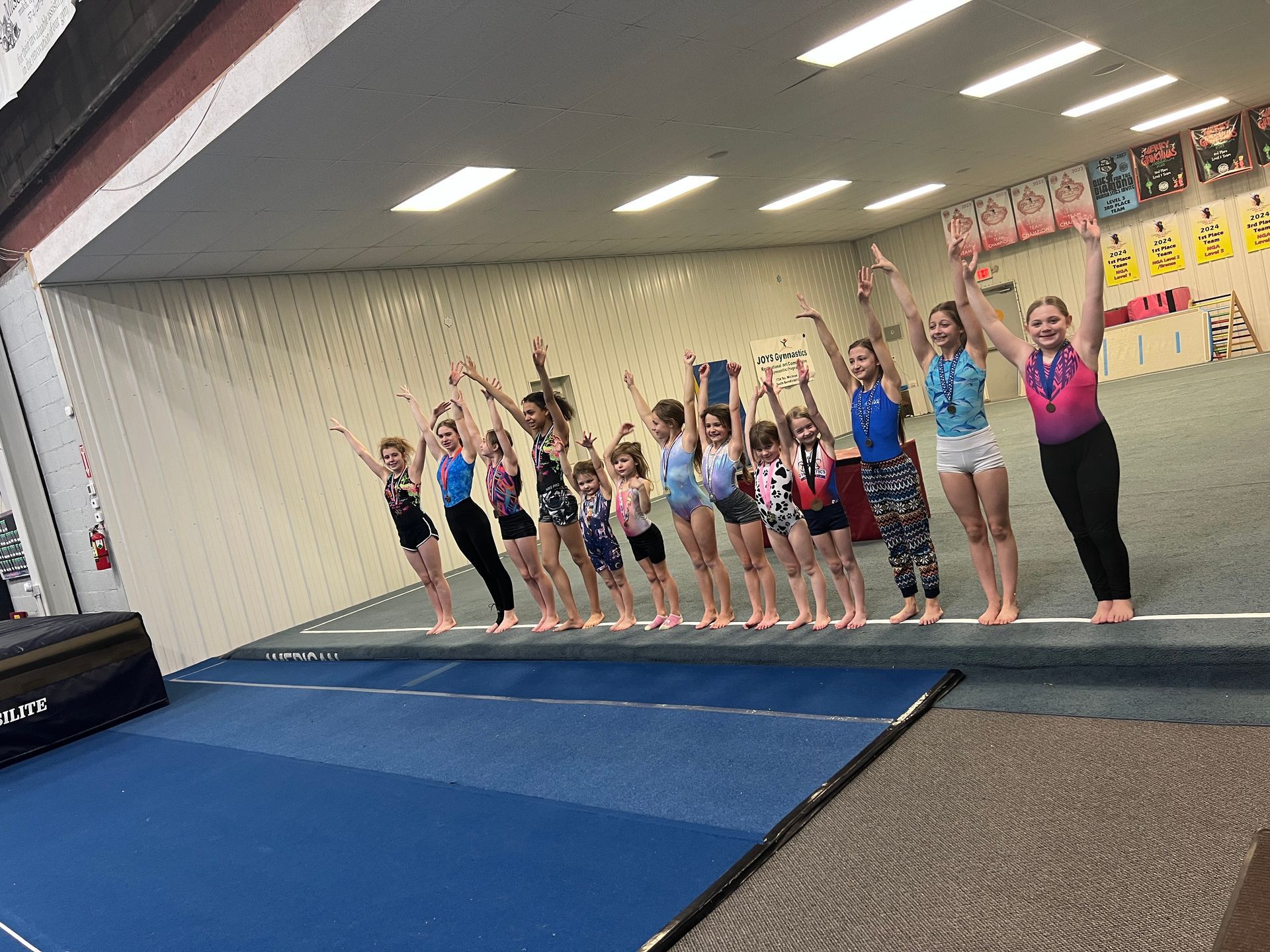 A group of young girls are posing for a picture in a gym.