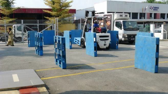 Forklift navigating a blue pallet course outside a building.