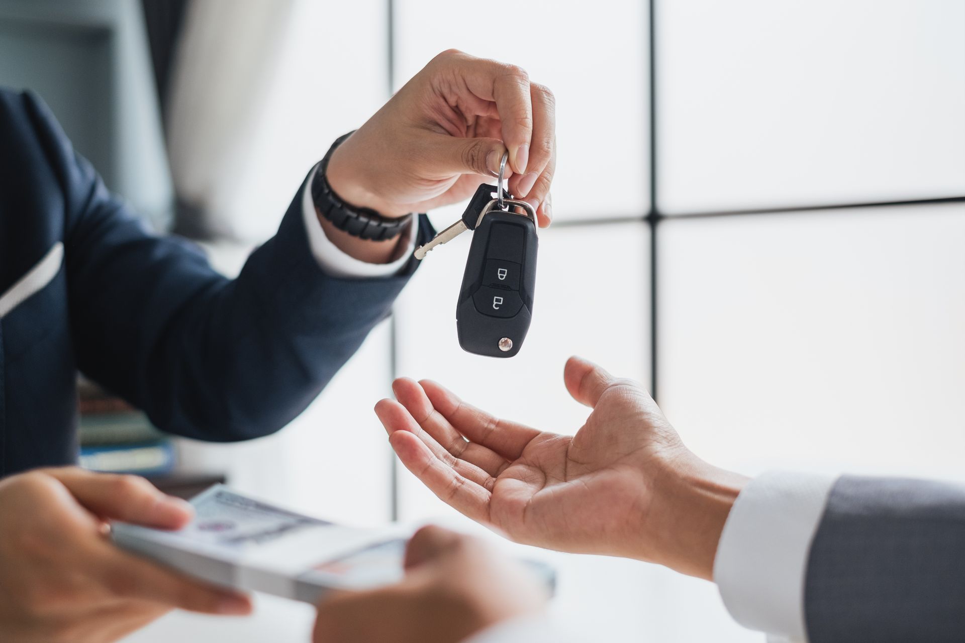 A man is handing a car key to another man.