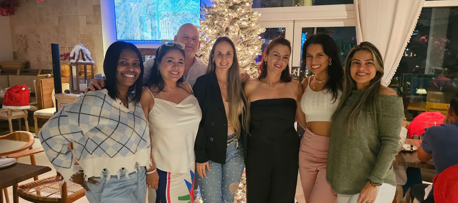 A group of women are posing for a picture in front of a christmas tree.
