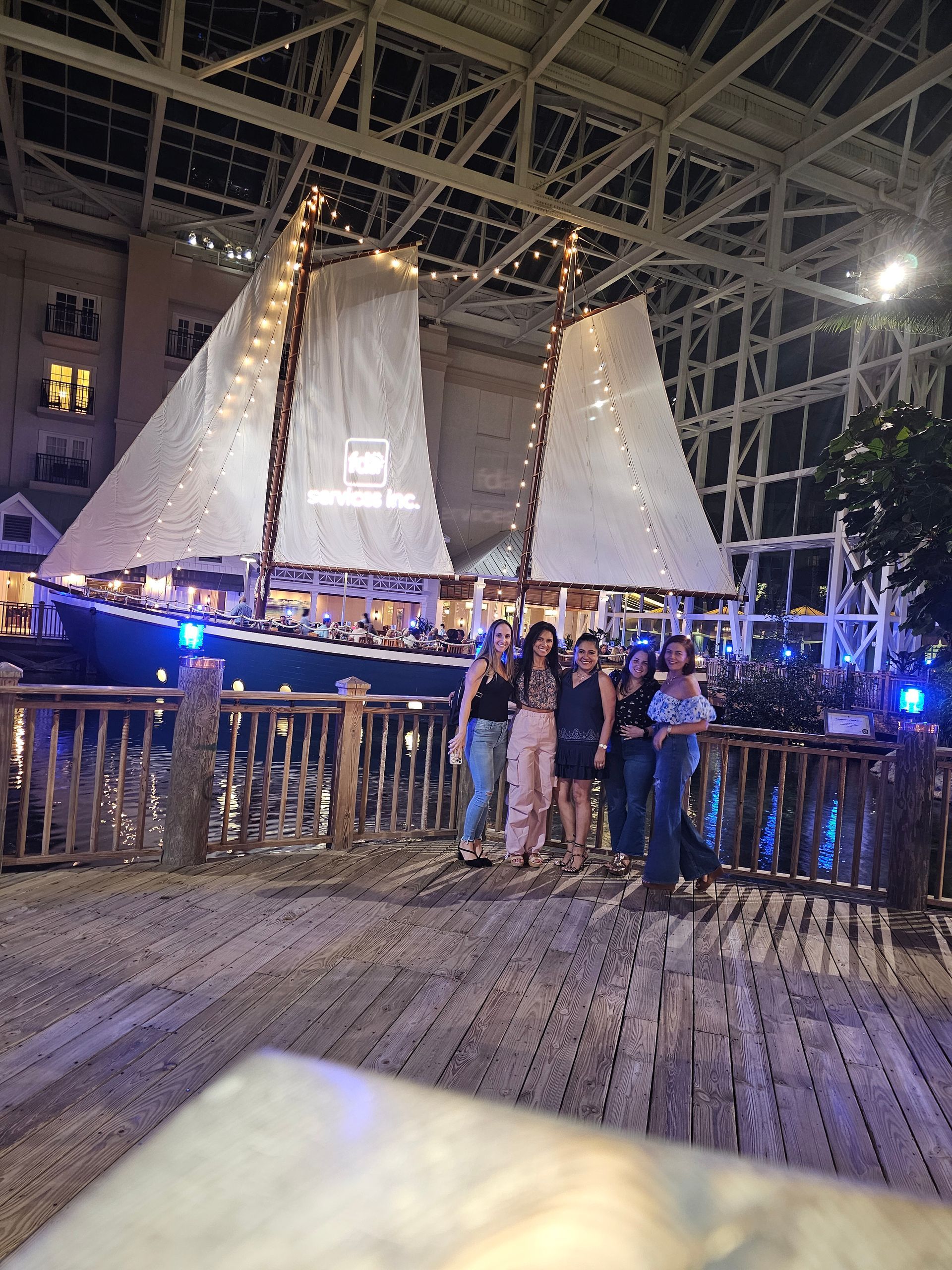 A group of people are posing for a picture in front of a sailboat.