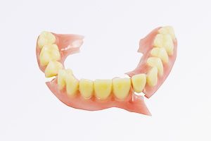 A broken denture with a lot of teeth on a white background.