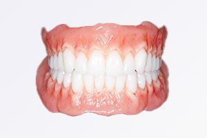 A close up of a denture with white teeth on a white background.