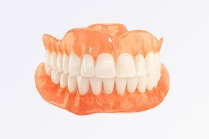 A full denture with white teeth on a white background.