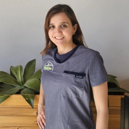 A woman wearing a gray scrub top with a logo on it
