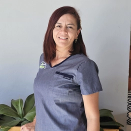 A woman in a blue scrub top is smiling for the camera