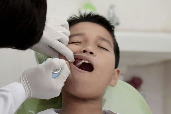 A young boy is getting his teeth examined by a dentist.