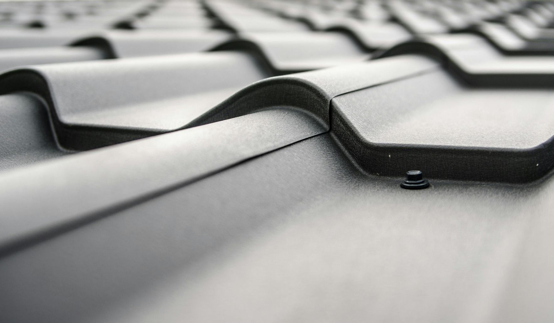 A close up of a black roof with a screw in it.