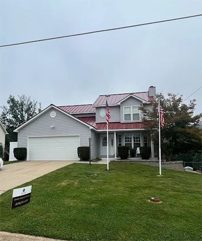 A large gray house with a red roof and a flag pole in front of it.