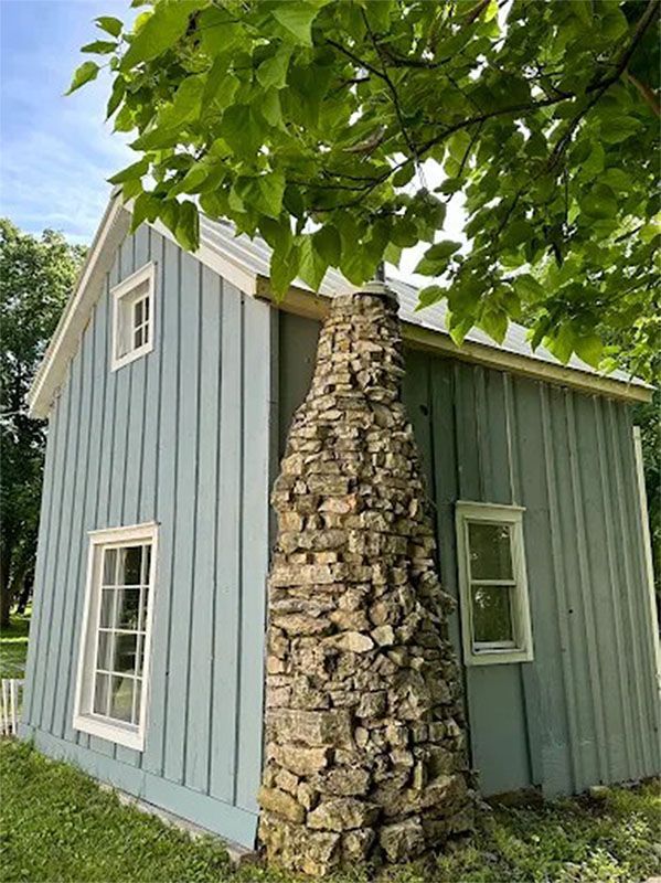 A small house with a stone chimney on the side of it.