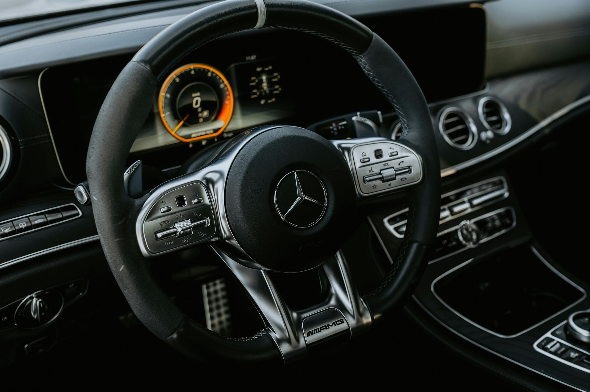 Black Mercedes-Benz steering wheel with silver accents, dashboard display visible.