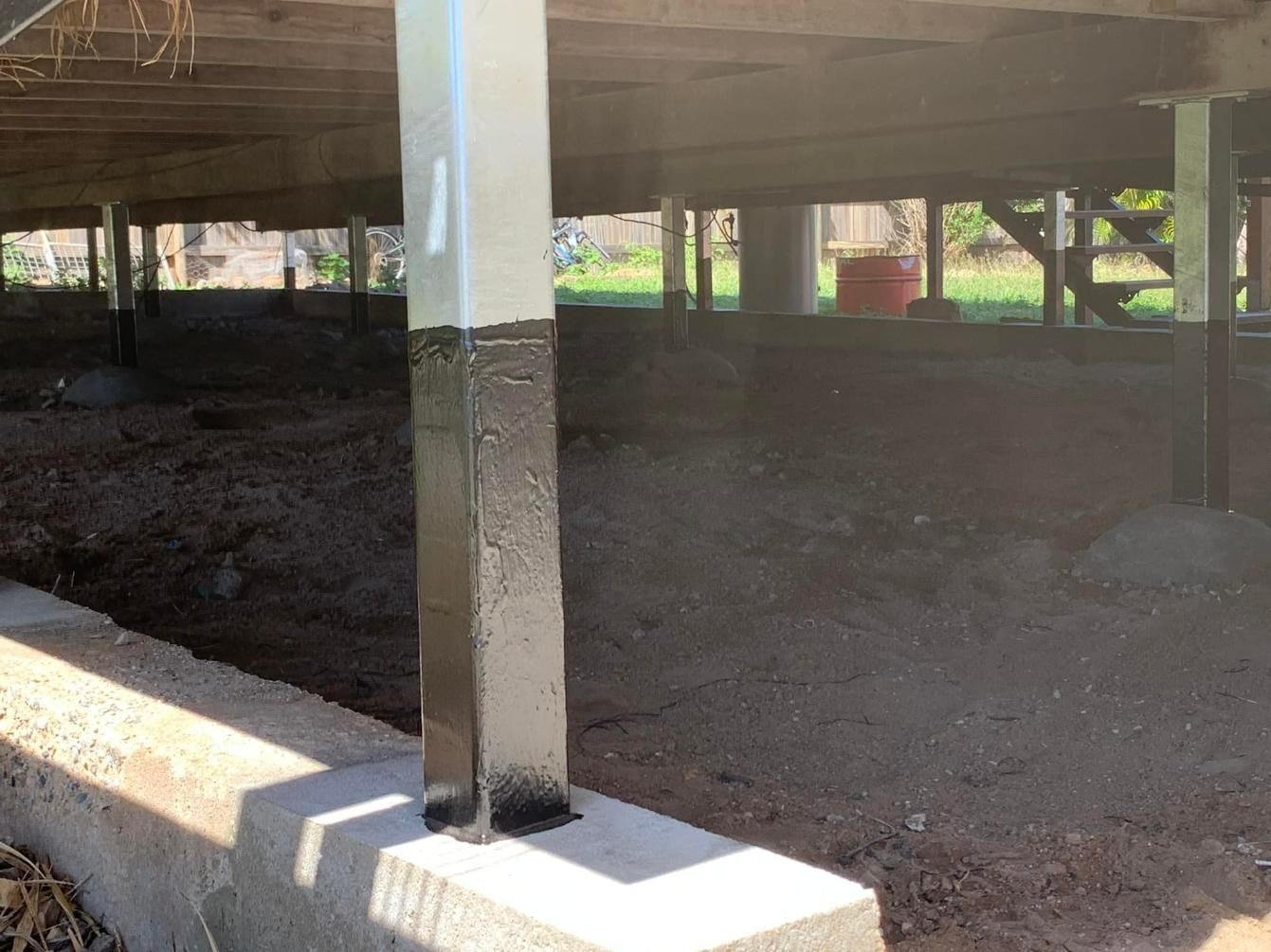 A Concrete Pillar Is Painted Black and White Under a House — Get Stumped Stumping & Maintenance In Collinsville, QLD