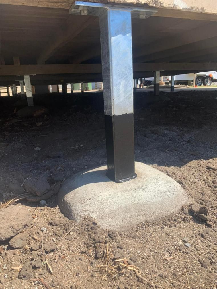 A Metal Pole Is Sitting on Top of A Concrete Base Under a House — Get Stumped Stumping & Maintenance In Ayr, QLD