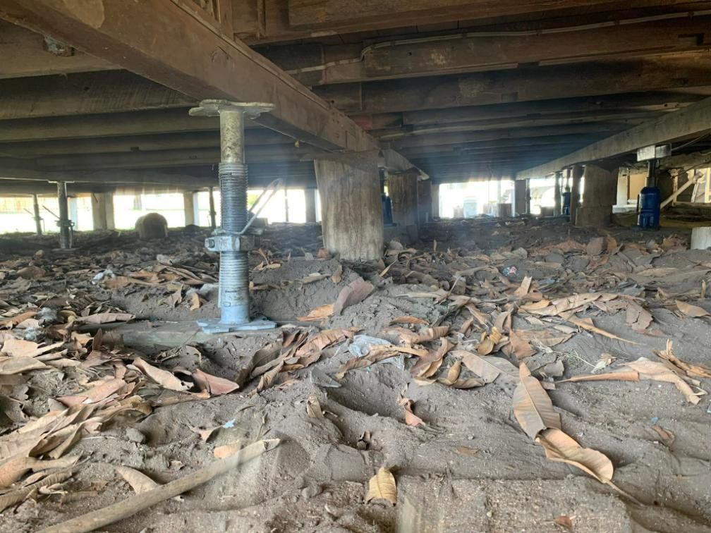 The Bottom of A Building Is Covered in Dirt and Leaves — Get Stumped Stumping & Maintenance In Ayr, QLD