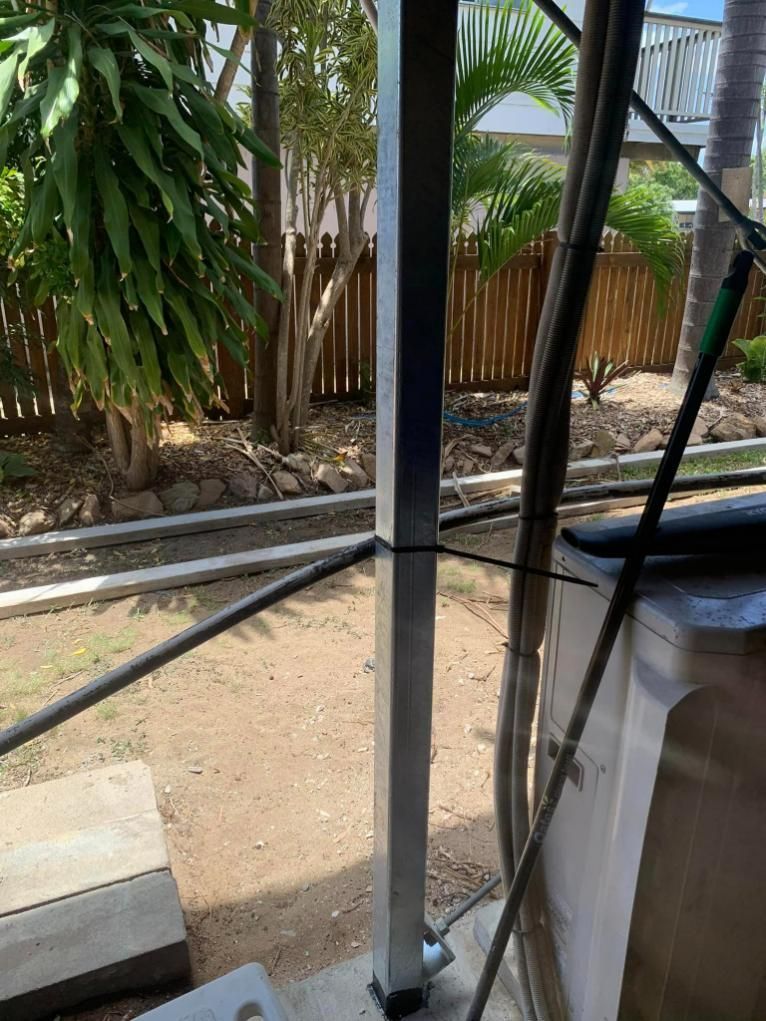 A Metal Pole Is Sitting in The Dirt Next to A Fence — Get Stumped Stumping & Maintenance In Bowen, QLD