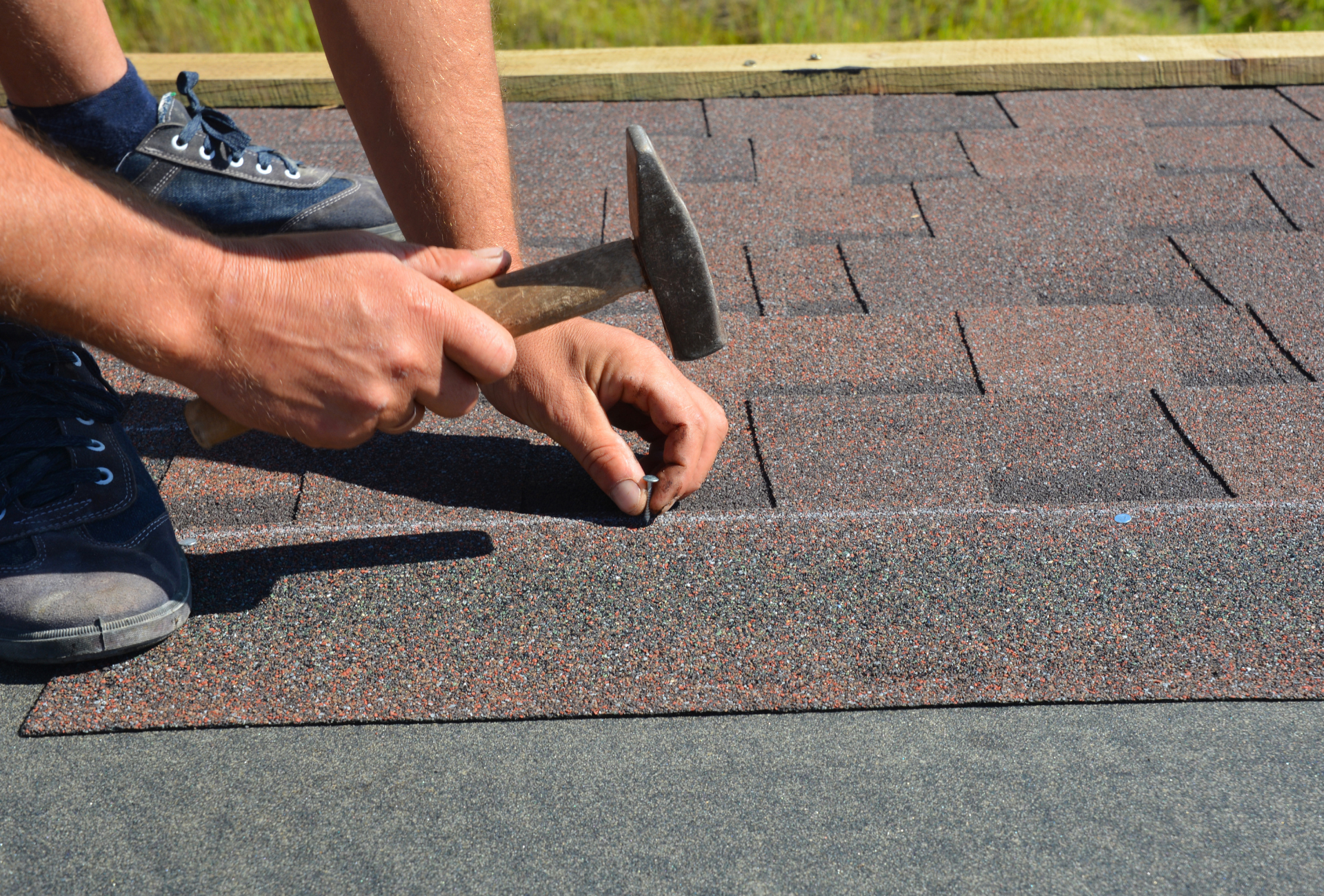 A man is hammering nails into a roof with a hammer.