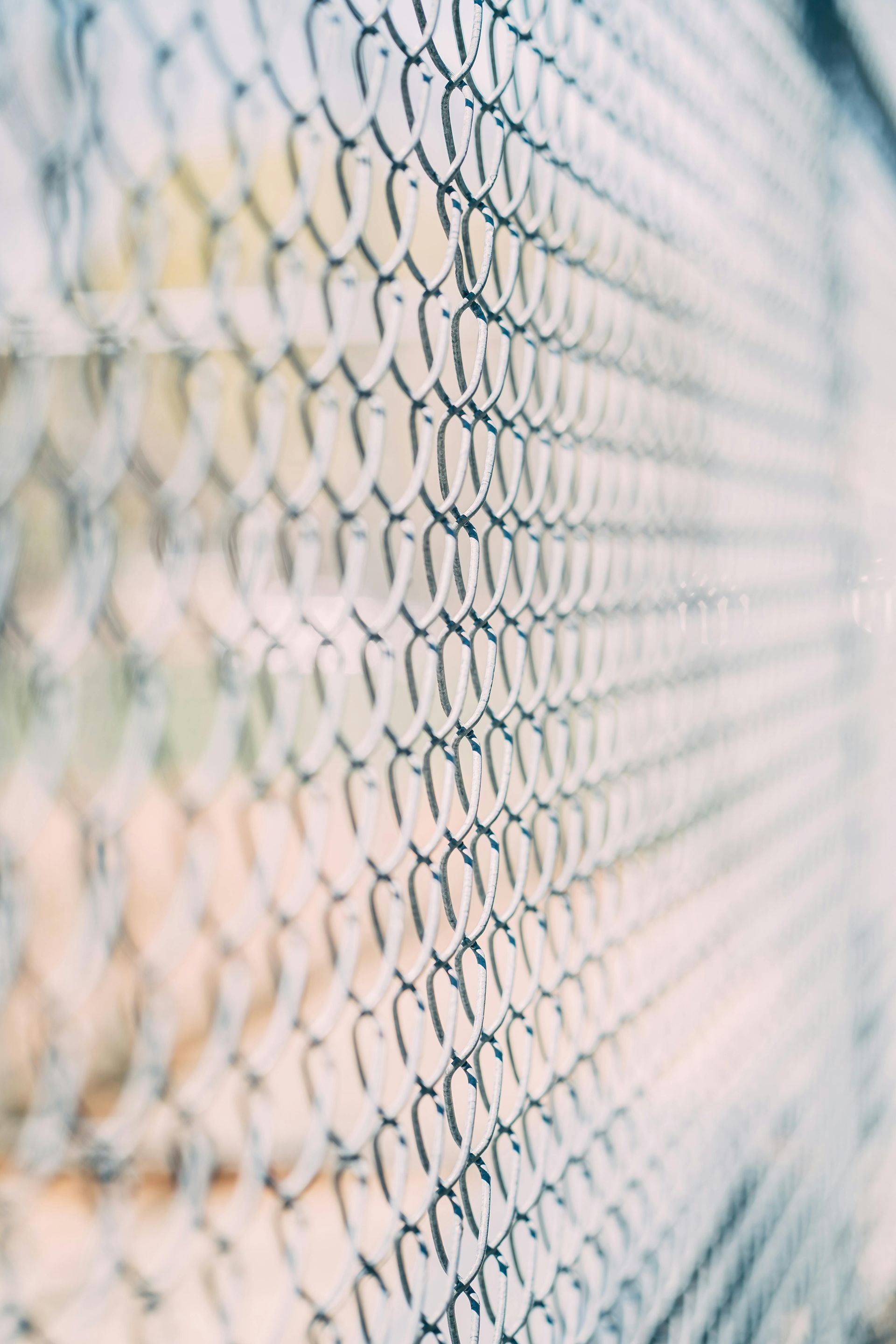 A close up of a chain link fence with a blurred background.