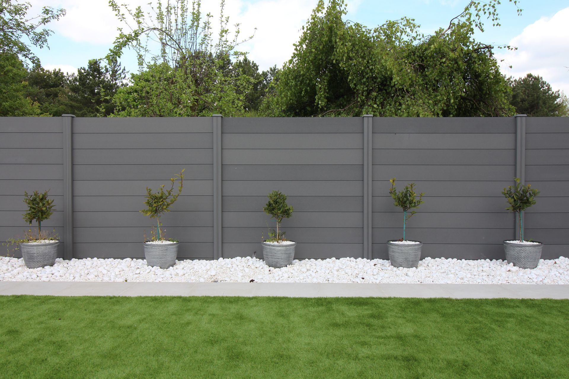 A gray fence with potted plants in front of it