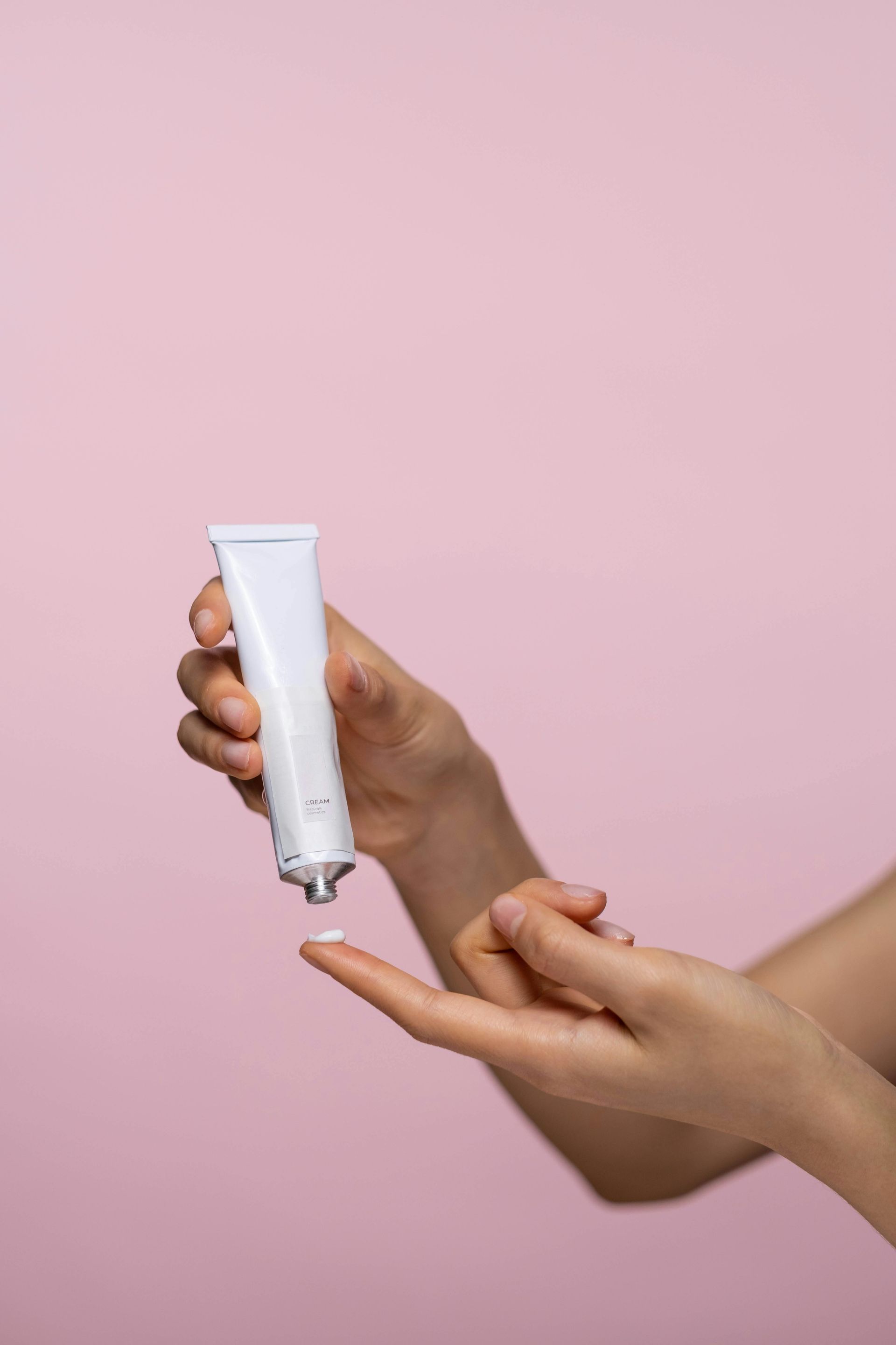 Una mujer sostiene un tarro de crema en tubo en sus manos.