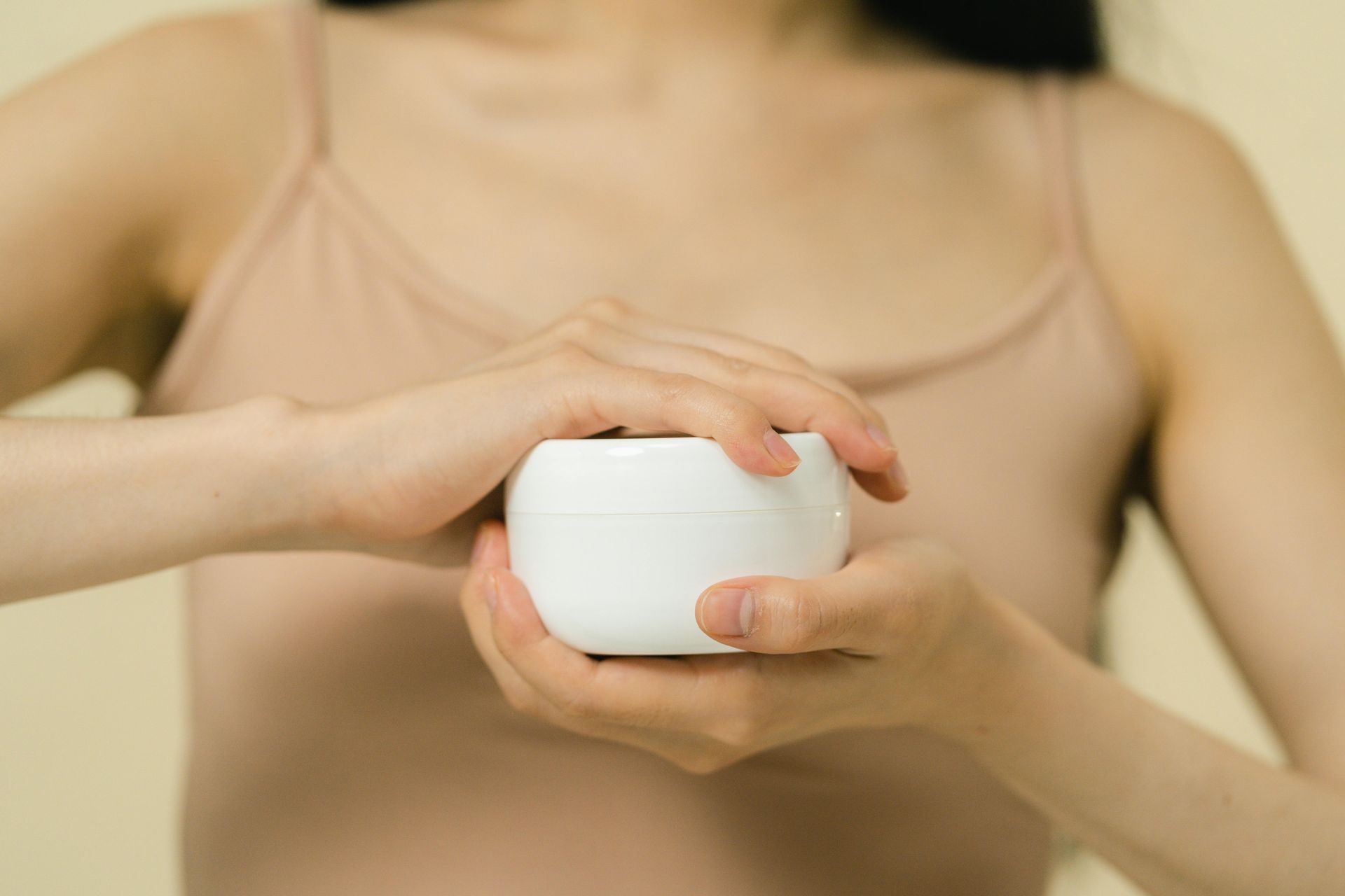 Una mujer sostiene un tarro de crema en sus manos.
