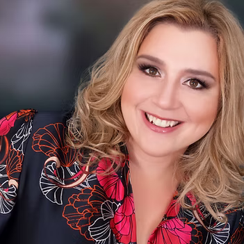 A woman in a floral shirt is smiling for the camera.