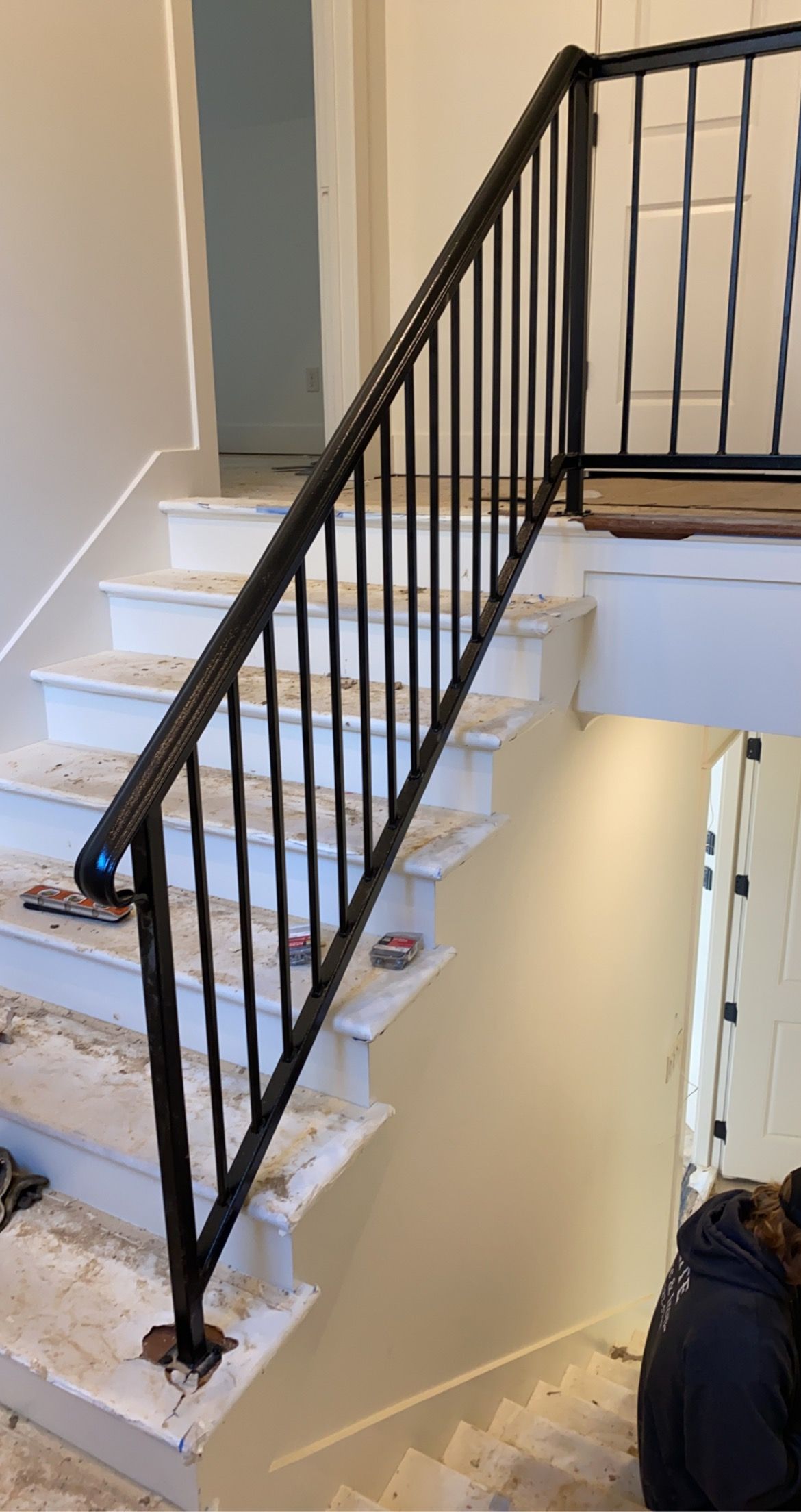 Black iron railing along a white staircase in a building.
