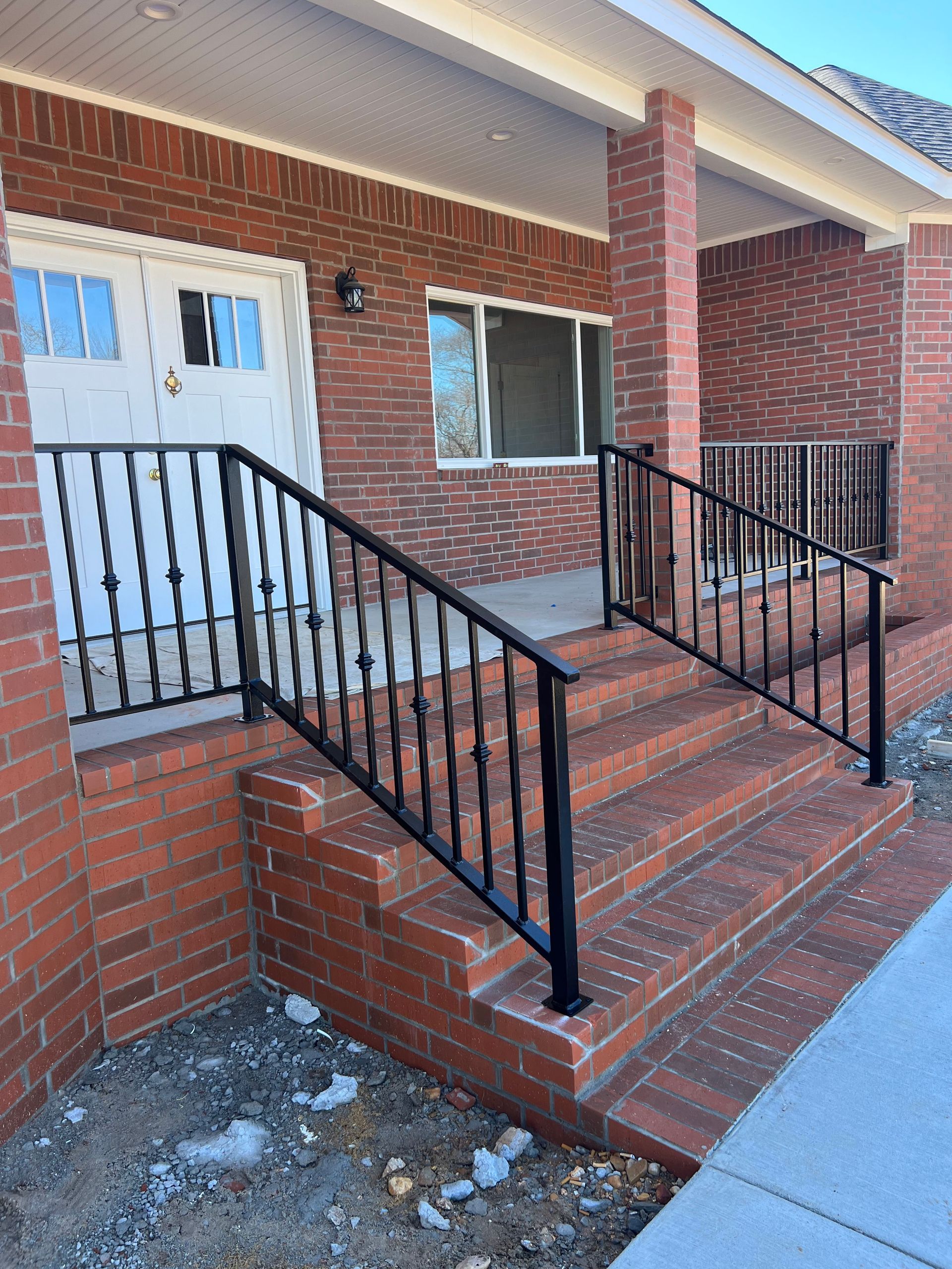 Brick home exterior with porch steps and black metal railings.