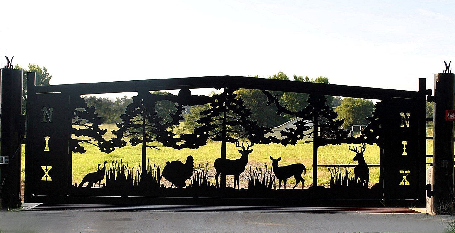 Silhouette of wildlife on a black metal gate, including turkey, deer, and trees. Green field in background.