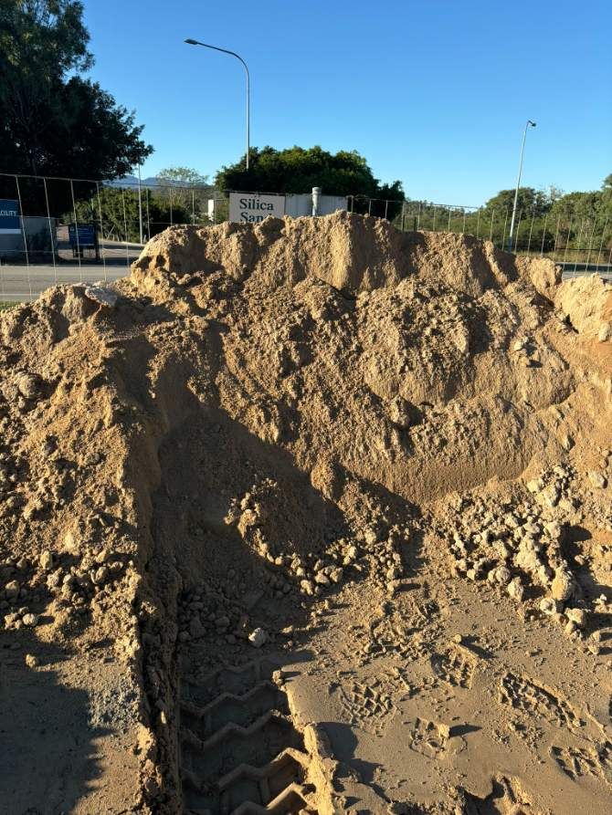A Pile Of Dirt Is Sitting On The Ground Next To A Road — McCahills Earthmoving & Landscaping Supplies In Stuart, QLD