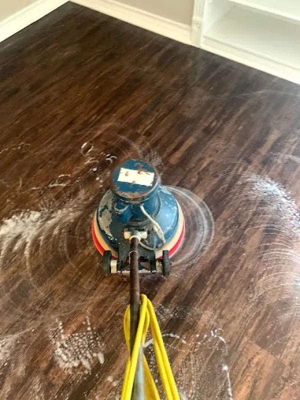 A vacuum cleaner is cleaning a wooden floor in a living room.