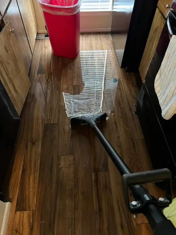 A mop is laying on the floor in a kitchen next to a trash can.