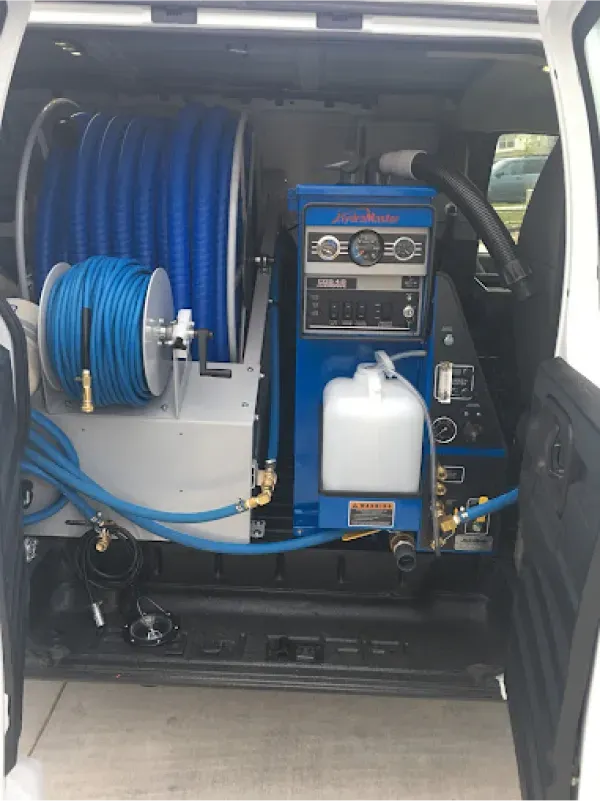 The back of a van with a machine and hose in it.