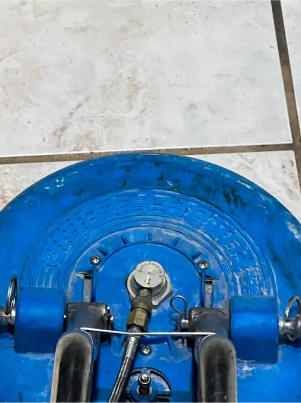 A blue vacuum cleaner is sitting on a tiled floor.