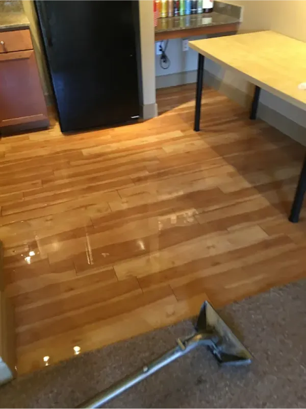 A vacuum cleaner is sitting on a wooden floor in a kitchen