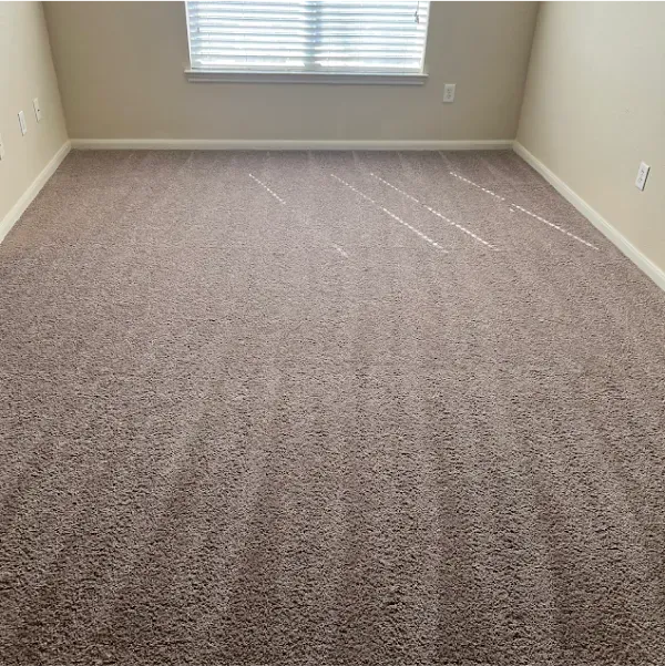A bedroom with a large carpeted floor and a window.