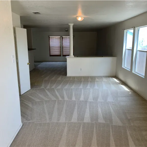 An empty room with a carpeted floor and white walls