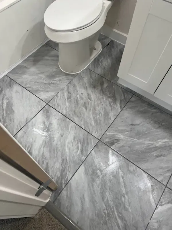 A toilet is sitting on a tiled floor in a bathroom.