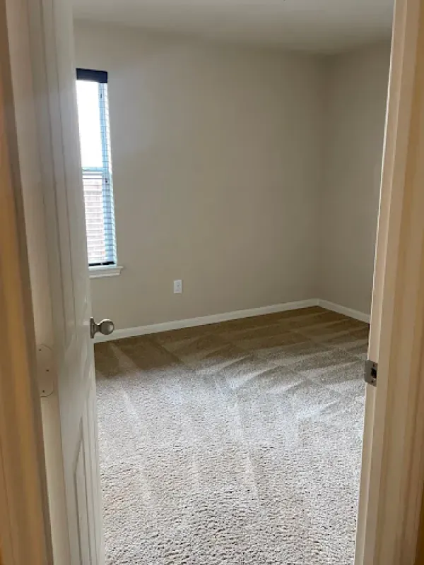 A bedroom with a carpeted floor and a window.