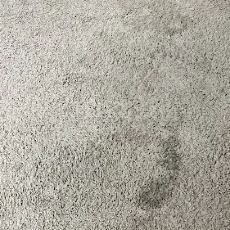 A close up of a white carpet with a stain on it.