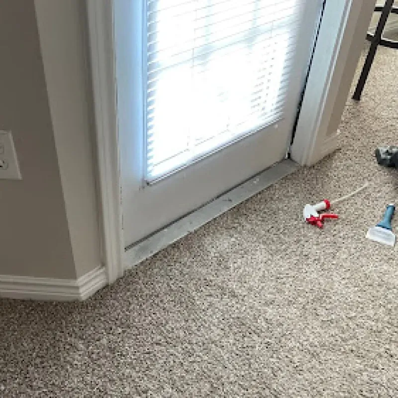 A carpeted floor in a living room next to a sliding glass door.