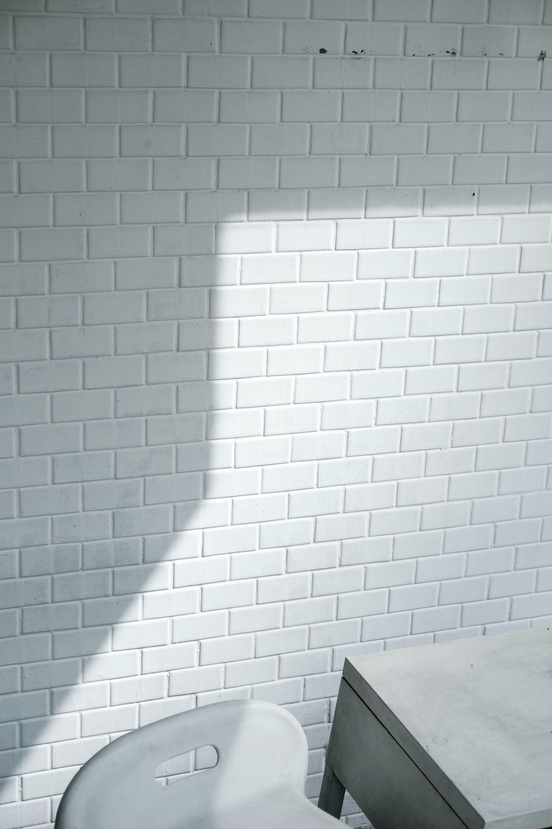 A white brick wall with a chair and a table in front of it.