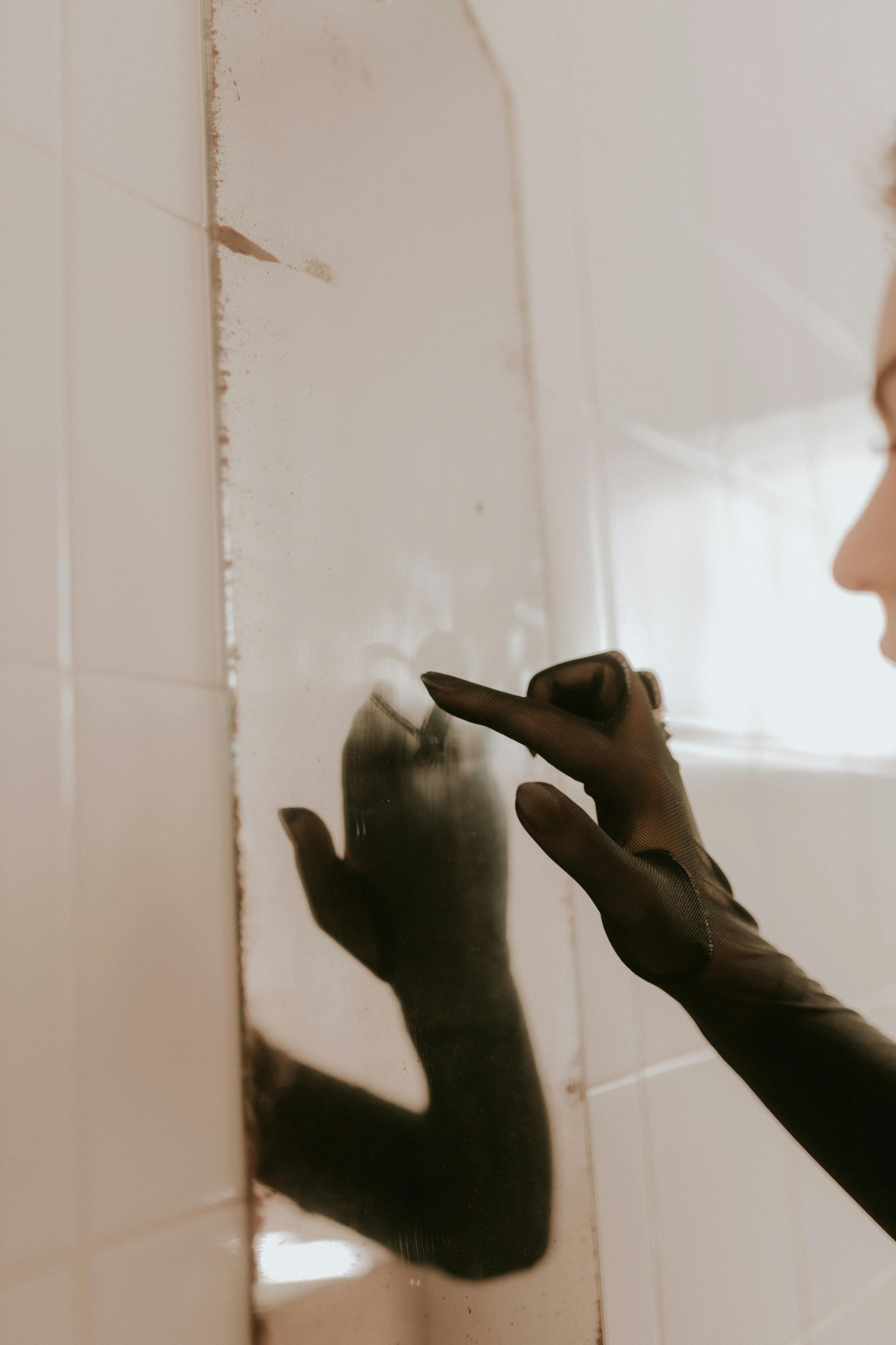 A woman is looking at her reflection in a mirror.