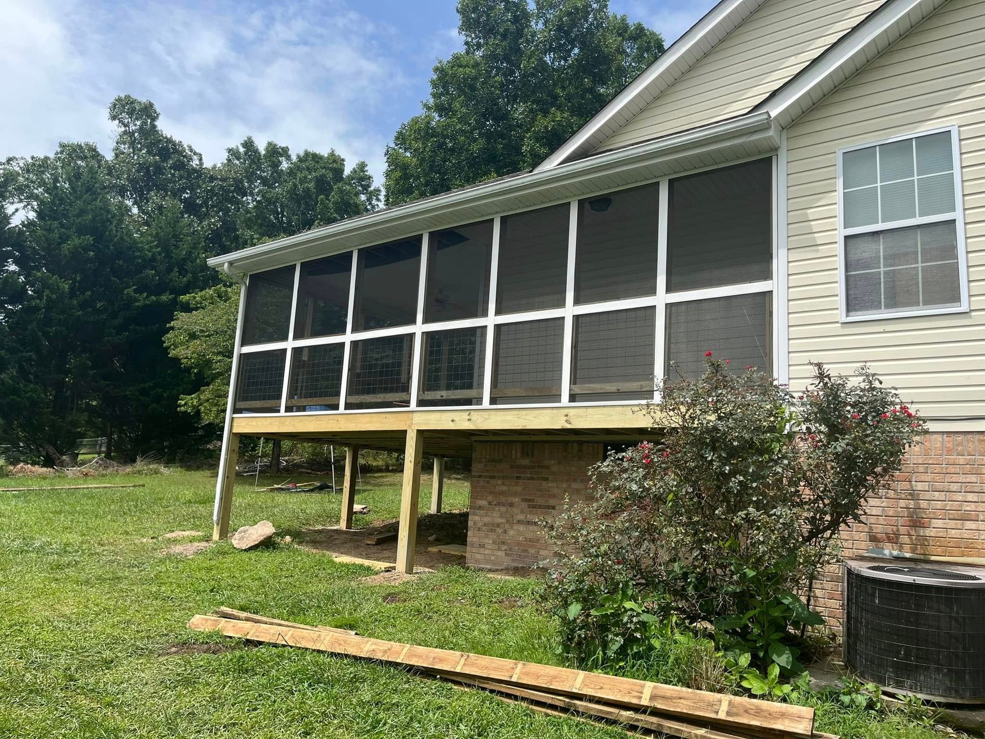 A screened in porch is being built on the side of a house.