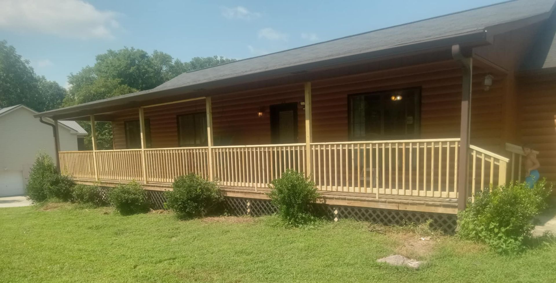 A log cabin with a large porch and a garage.